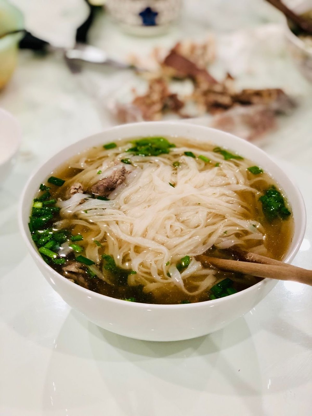 A bowl of pho with herbs and lime on the side